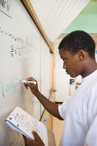 A student solves a problem on a dry-erase board